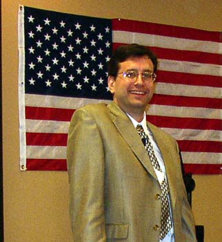 a man in suit standing near a flag