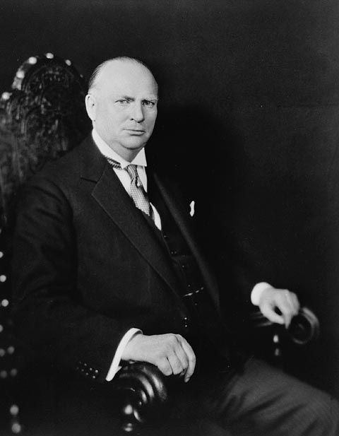 a man sitting on a chair wearing a suit and tie