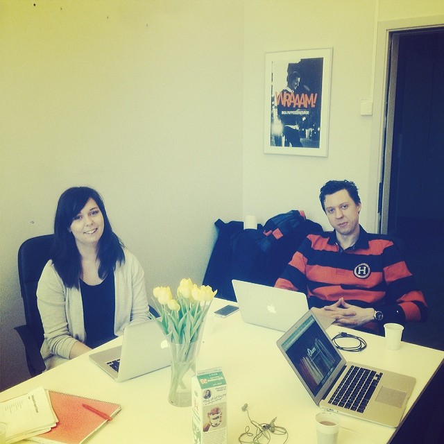 two people sitting at a table, with laptops and flowers in front of them