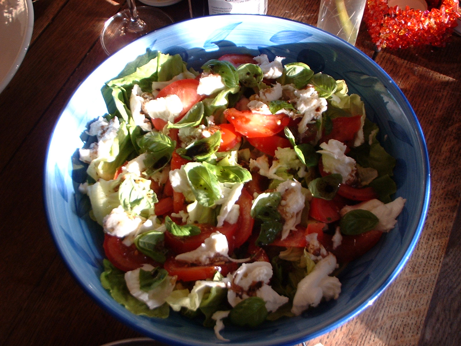 a bowl with salad has tomatoes, cheese and lettuce in it