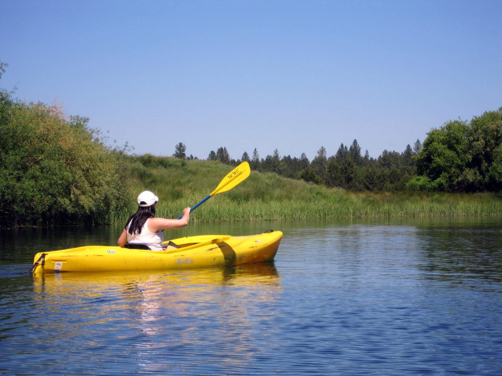 a person is paddleboarding on a calm river