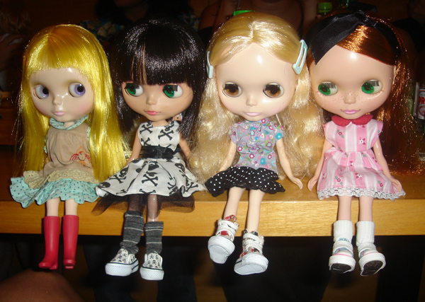 several doll's with clothes that appear like dresses sitting next to each other