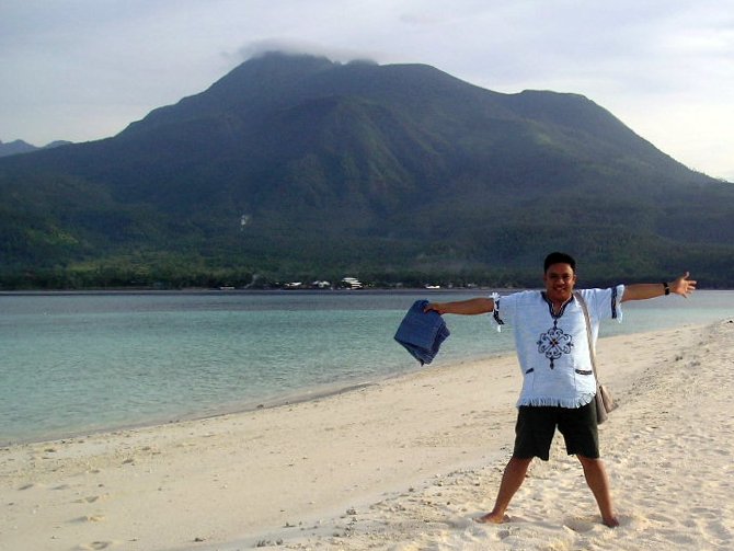 a man is standing on a beach in front of some water