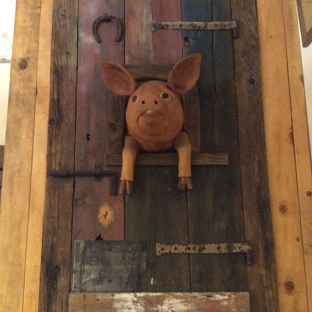a toy pig on a wooden door hanging on the wall