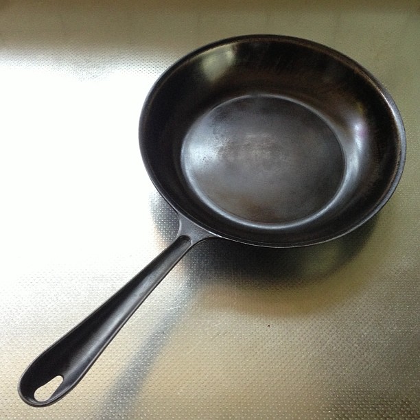 an iron pan sits on a table and looks worn
