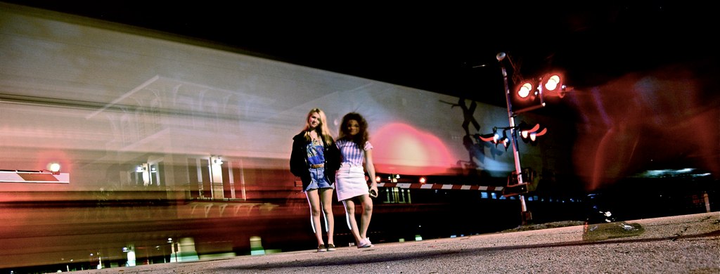 a couple of women standing on top of a street next to a bus