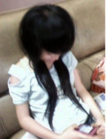 an asian girl with long dark hair sitting on a couch