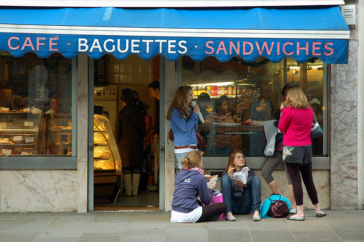 a group of people standing outside of a bakery