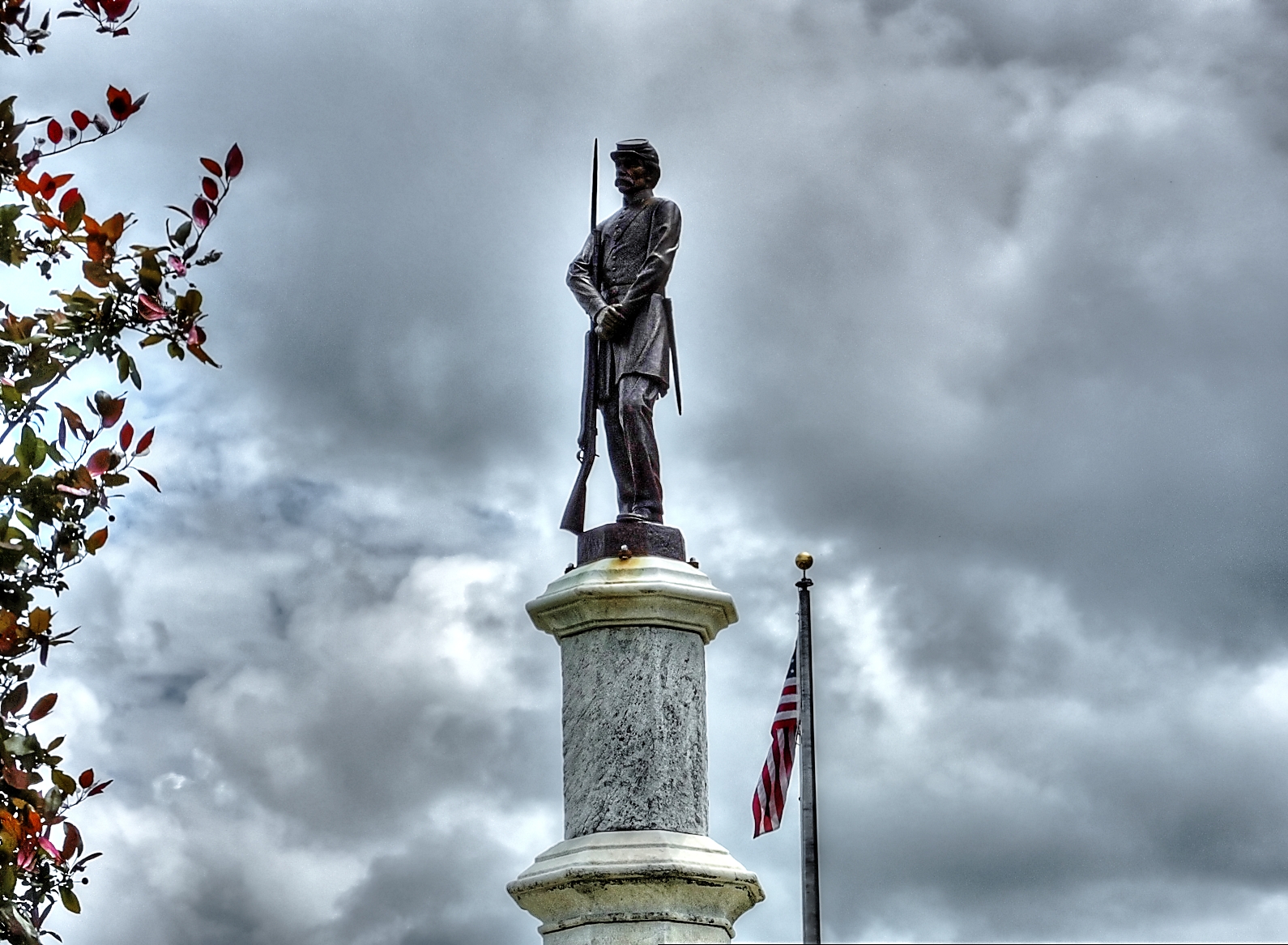 the statue has a flag in it and two flags flying beside it