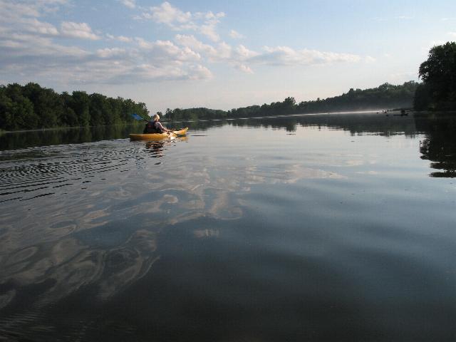 a person kayaking down a river near the woods