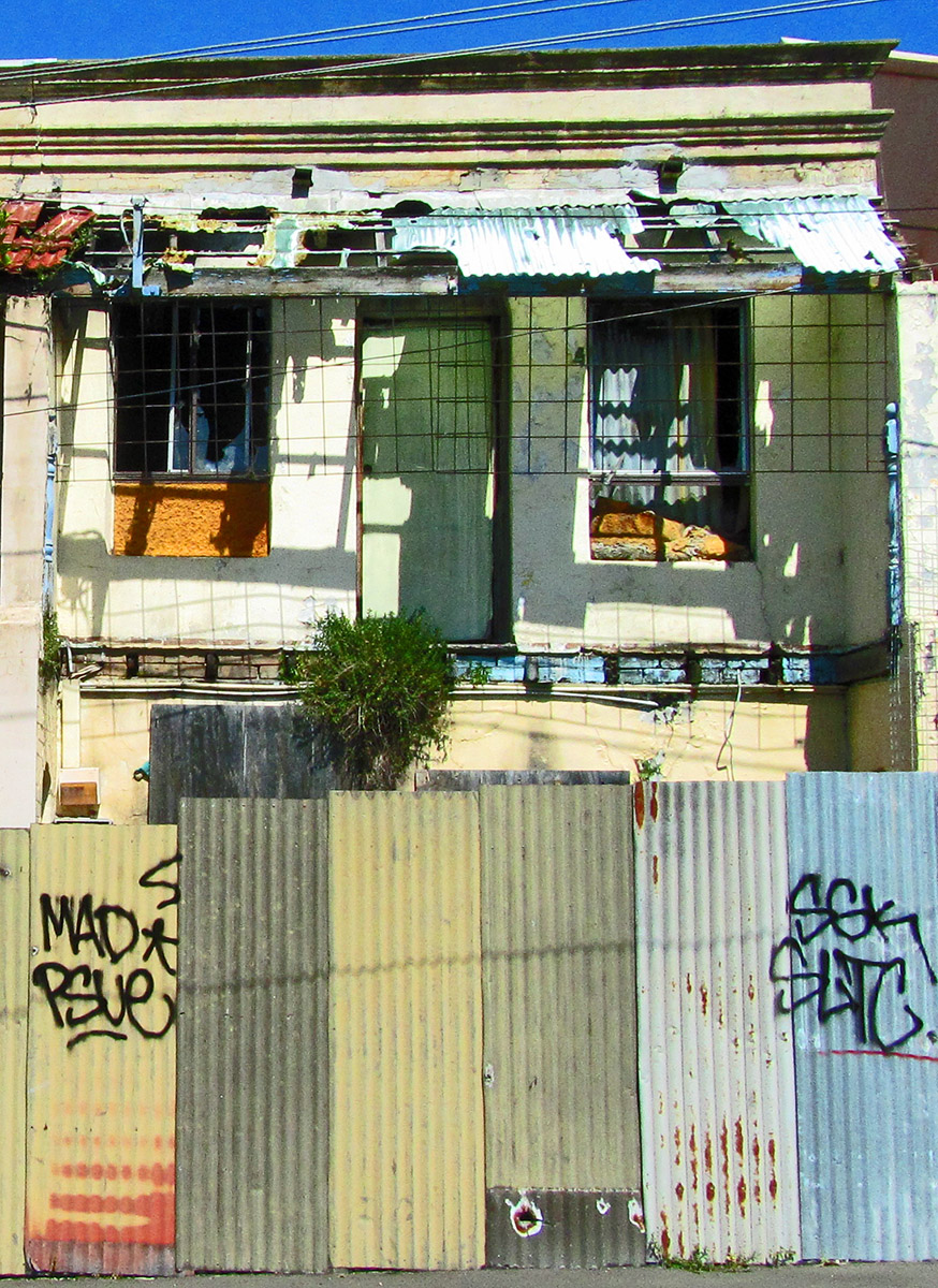 the front of an old run down house with graffiti on the windows and a balcony