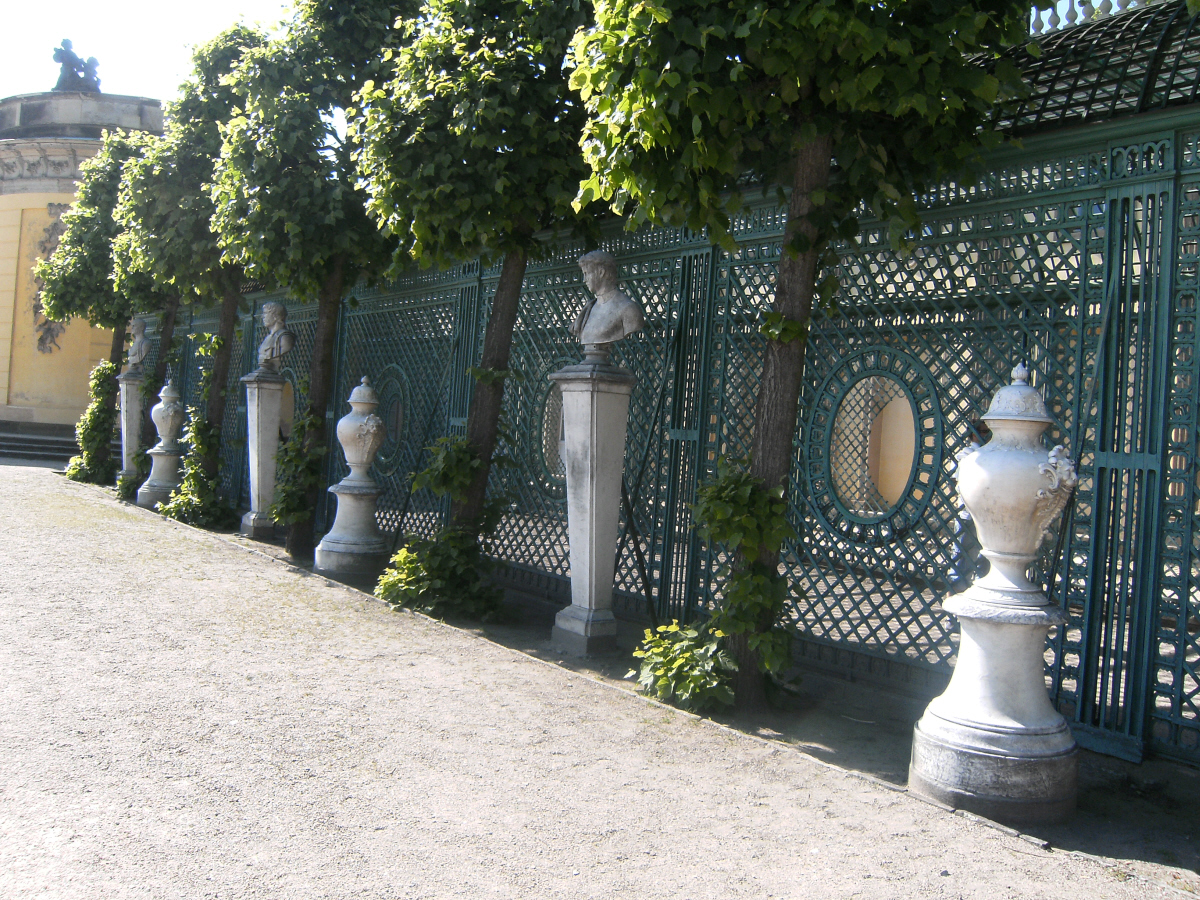 a line of decorative, cast iron fence with planters on each side