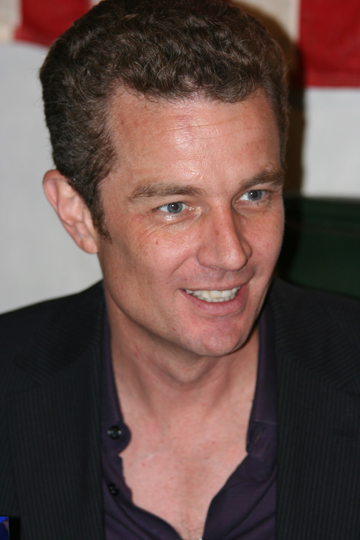 a man in a dark jacket smiles at the camera