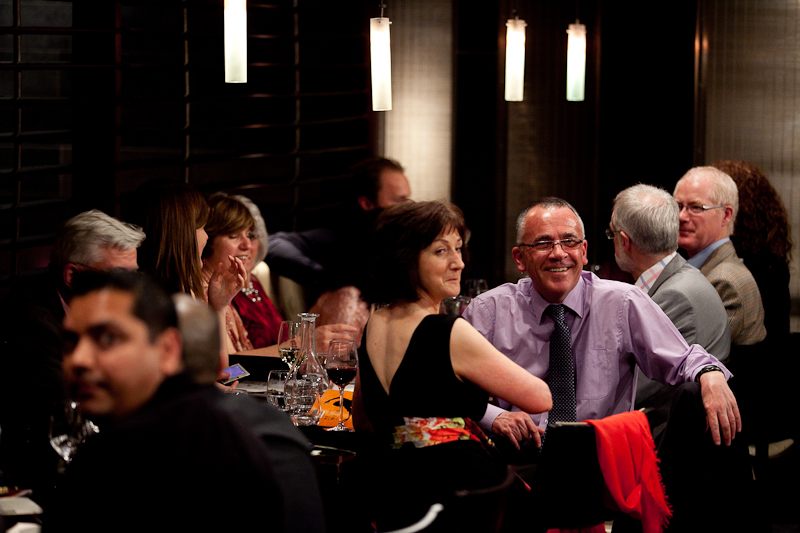 a group of people sitting at a long table, eating