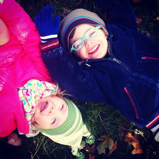 two little girls laying on the ground wearing jackets