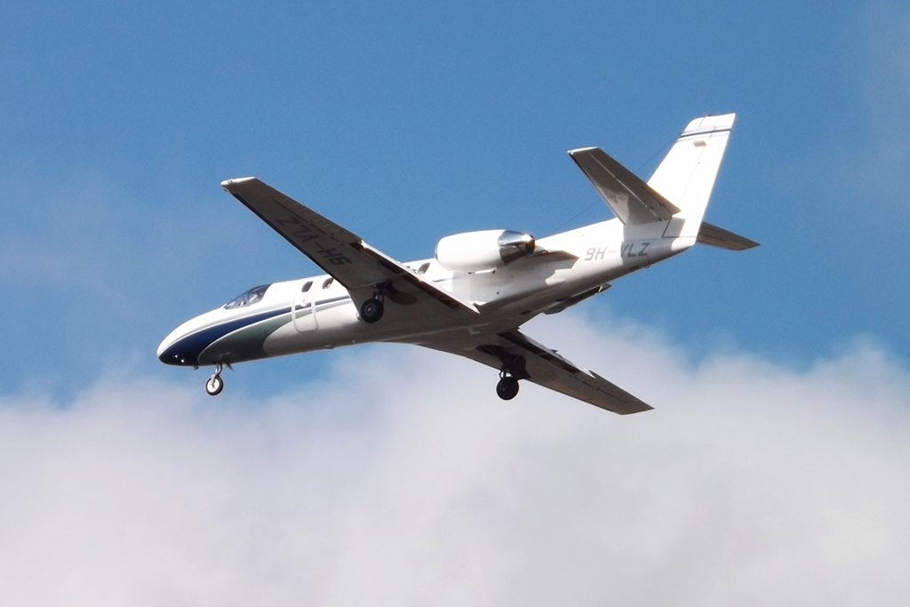 a propeller plane flying through the sky under a blue and white cloud