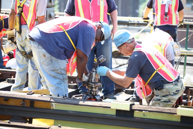 workers and their equipment on a large piece of steel