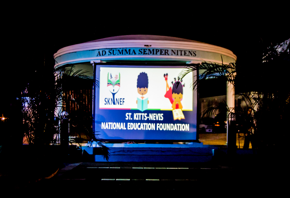 lighted advertit in front of a white structure with two women in costumes