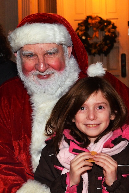 a small girl next to santa clause and a christmas tree