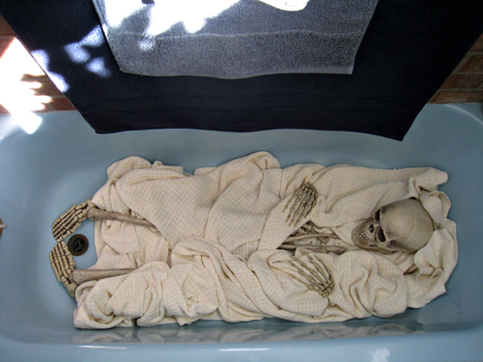 a baby in a bath tub with skeleton hands