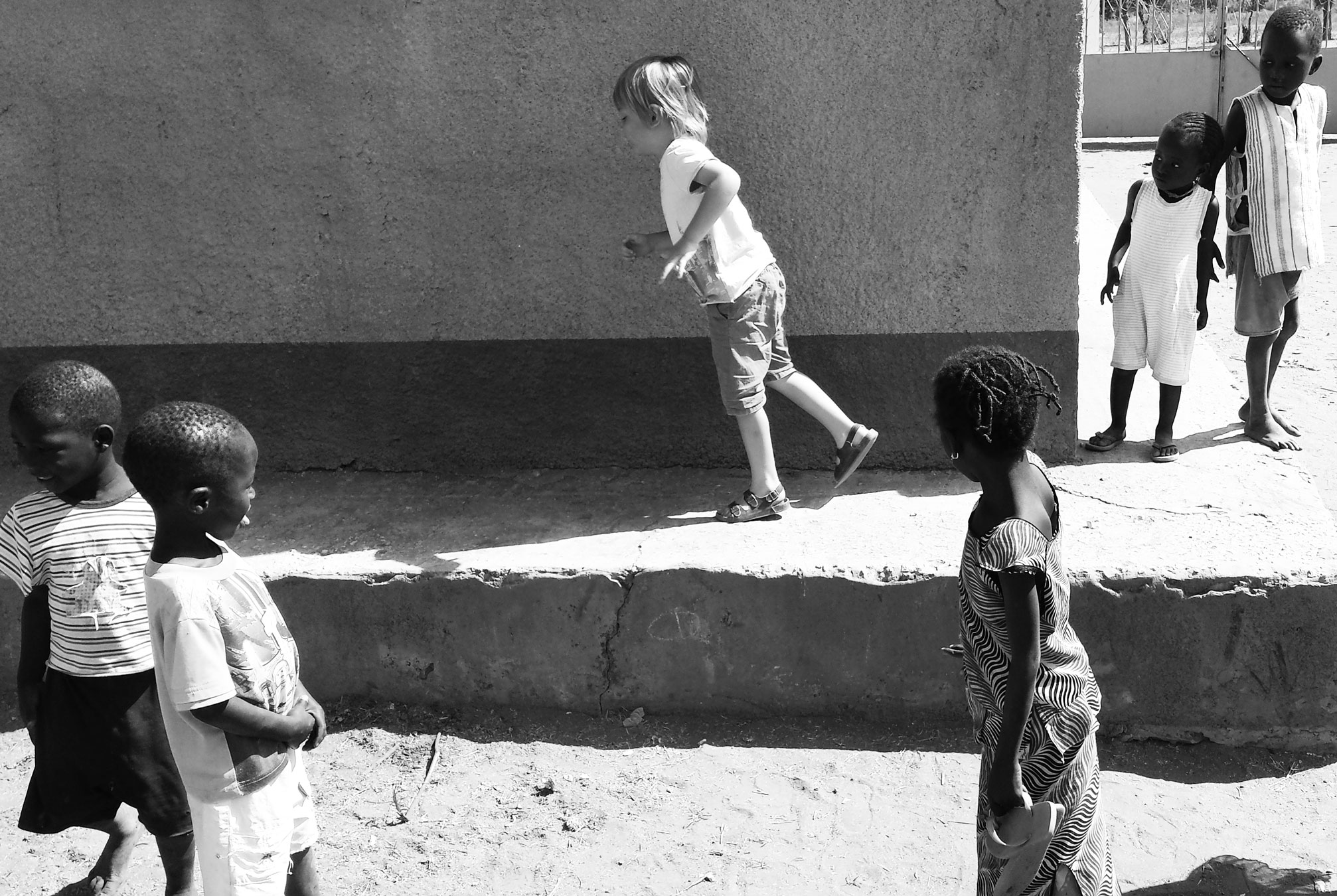 children in african outfits play with an adult