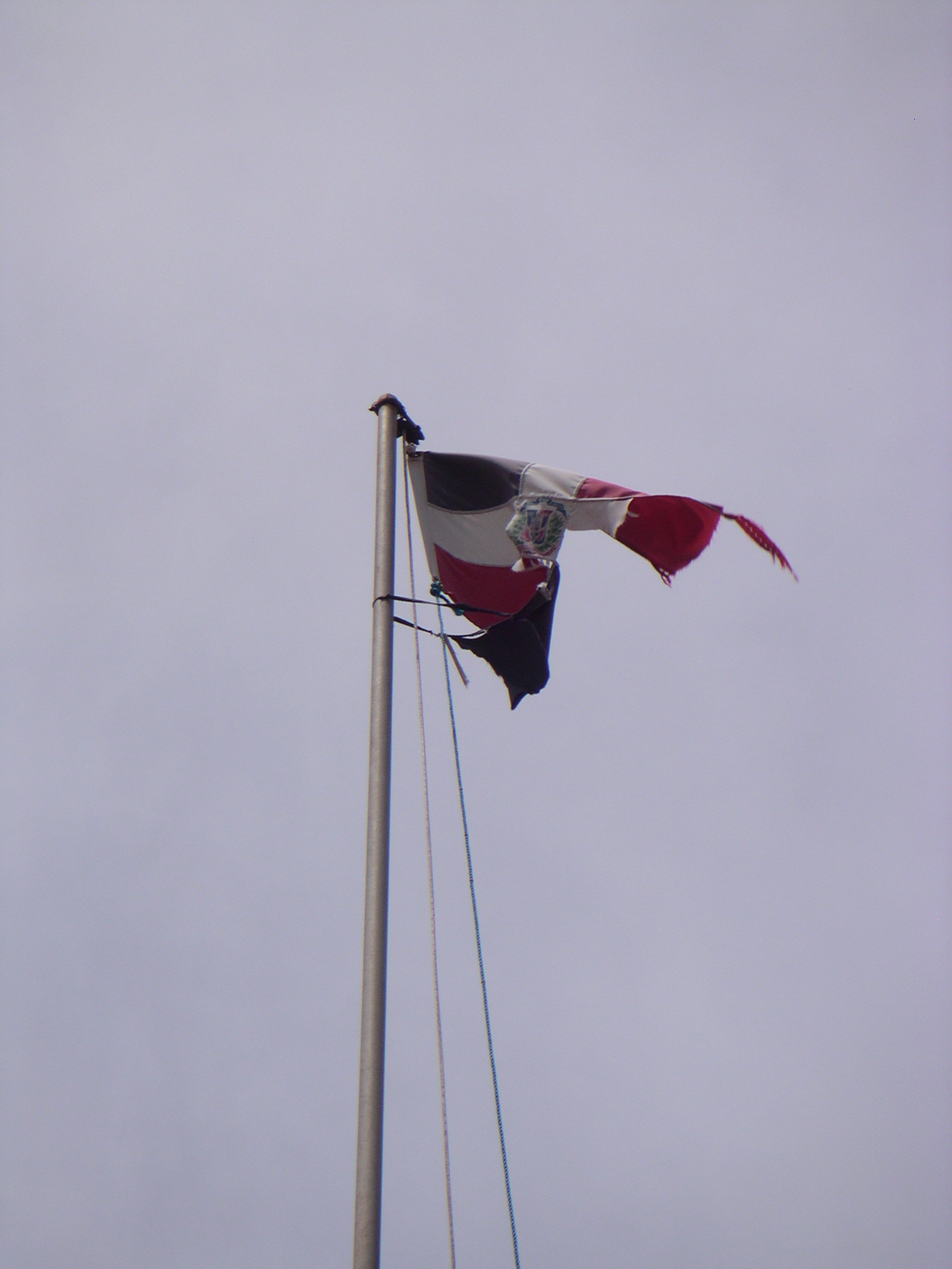 a flag flies high in the air with another flag blowing behind it