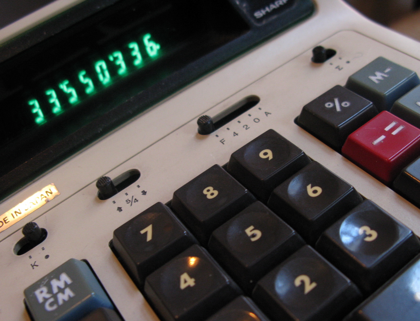 a black, red and grey calculator is next to a green clock