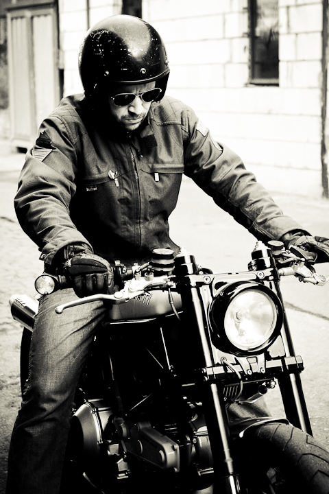 a black and white po of a man wearing glasses riding a motorcycle