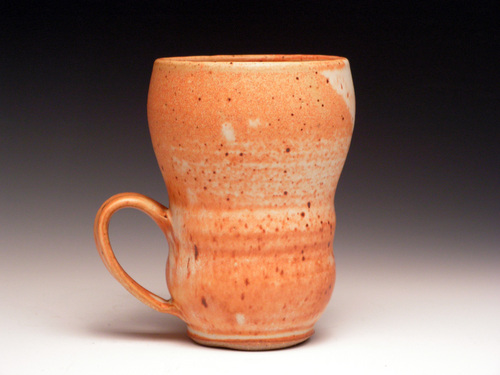 a ceramic cup with brown speckles is on a white surface