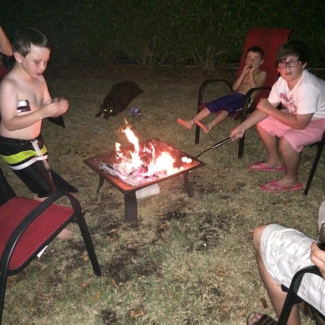 several people in chairs around an outdoor campfire