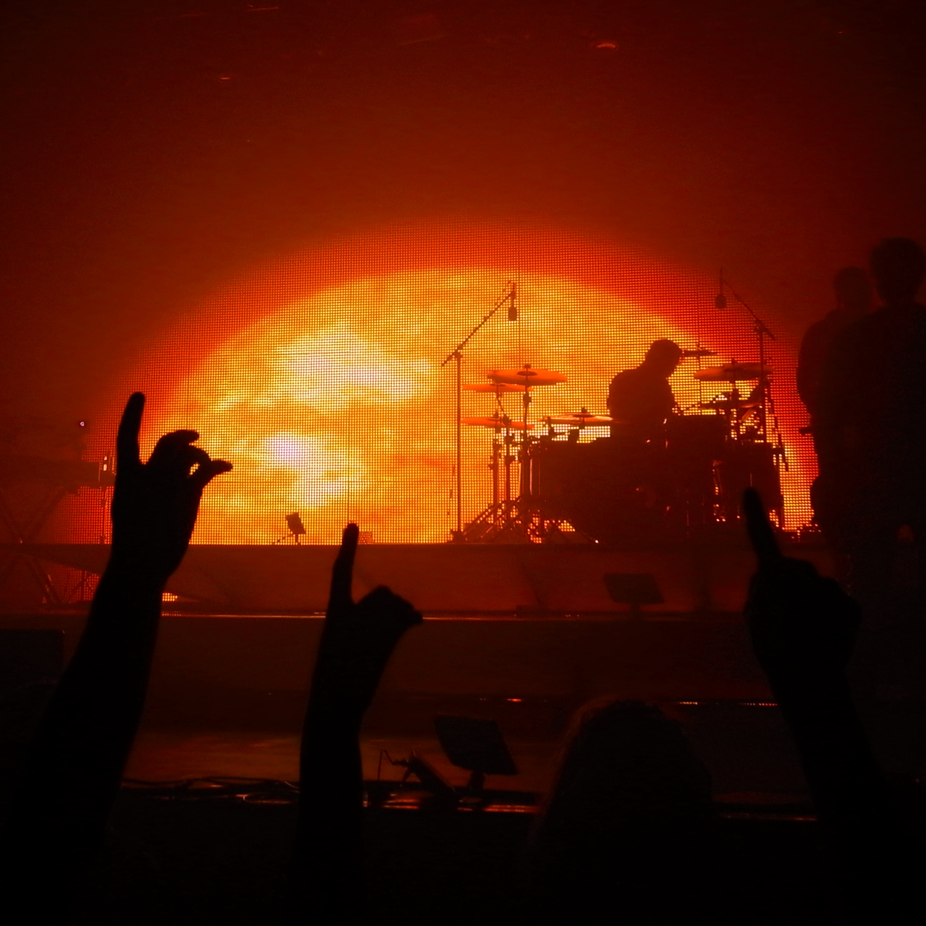 a group of people waving their arms while standing in front of a stage