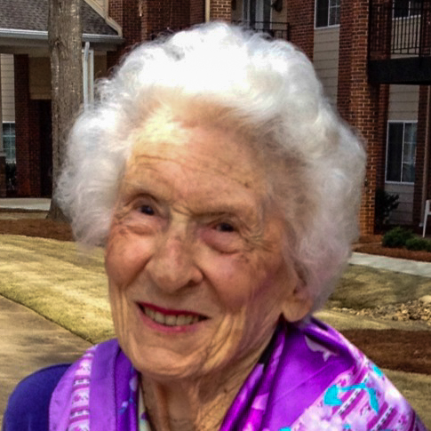 an old woman smiles as she holds a cellphone