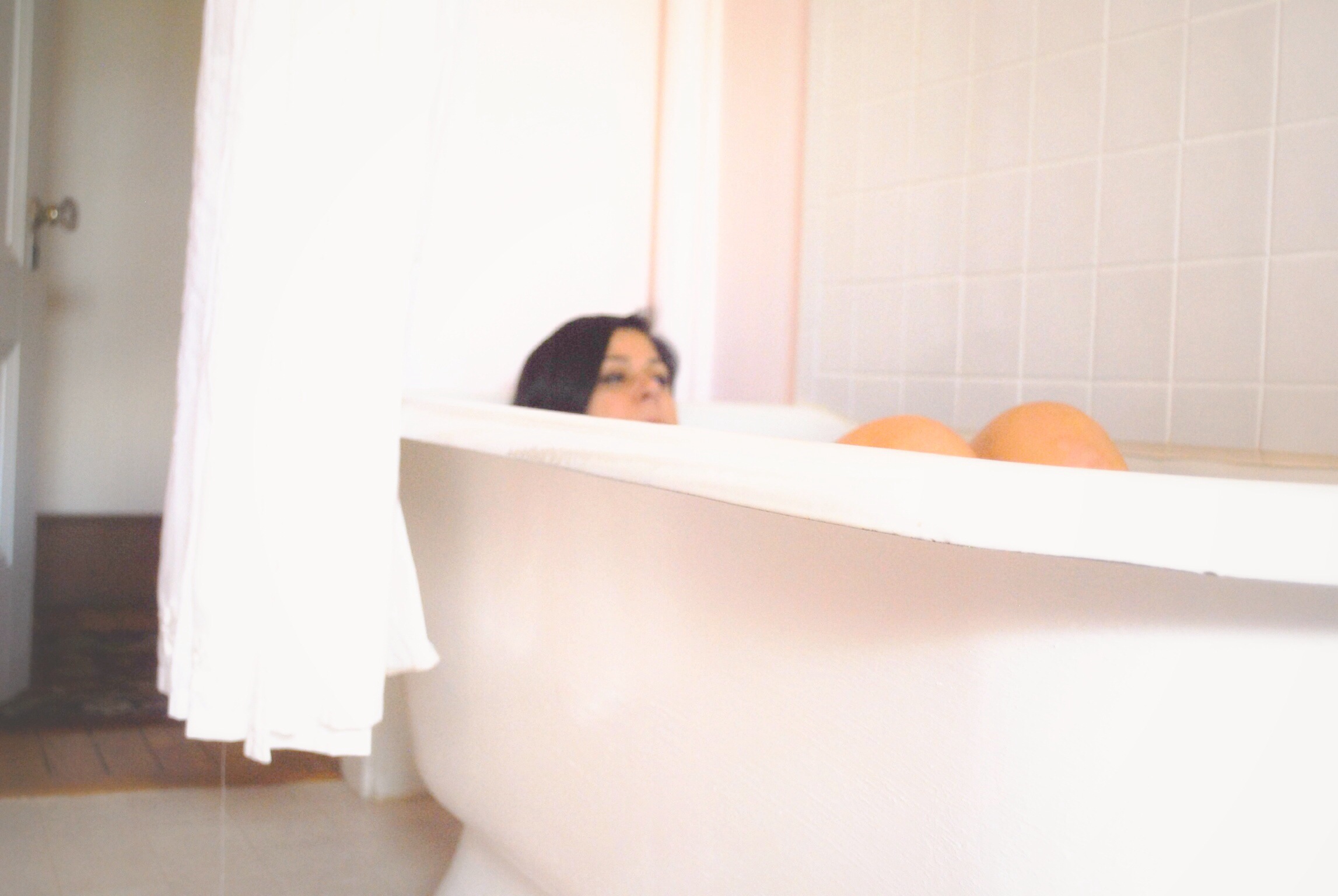 a woman is sitting on the edge of an old bath tub and staring