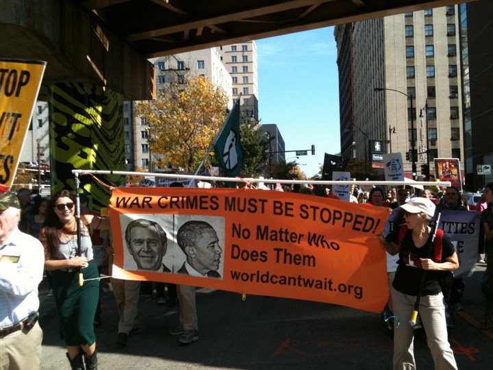 protesters holding a sign protesting a war crime against george w bush