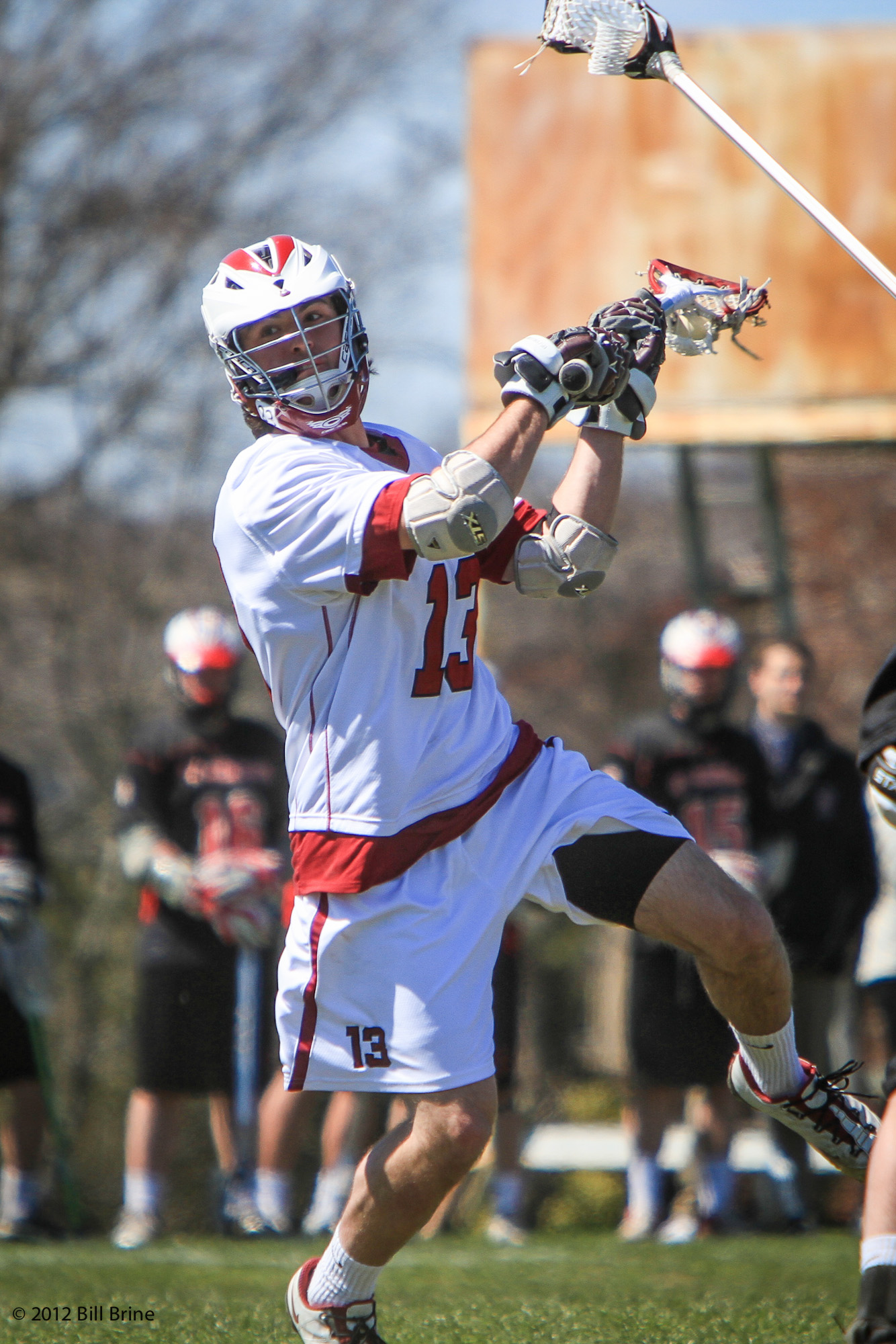 a man in white shirt and black shorts playing lacrosse