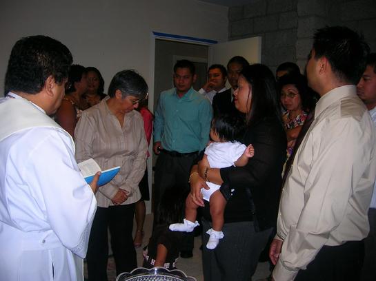 a woman holding a baby between people in the hallway