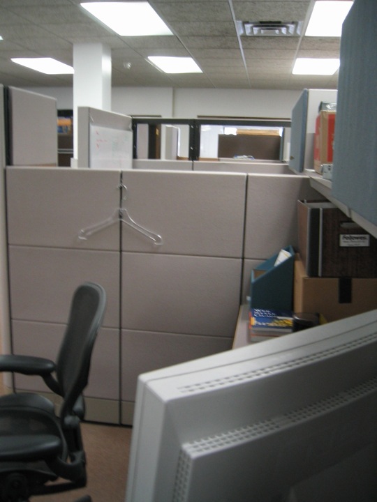 an office cubicle with several file drawers and a computer on the floor