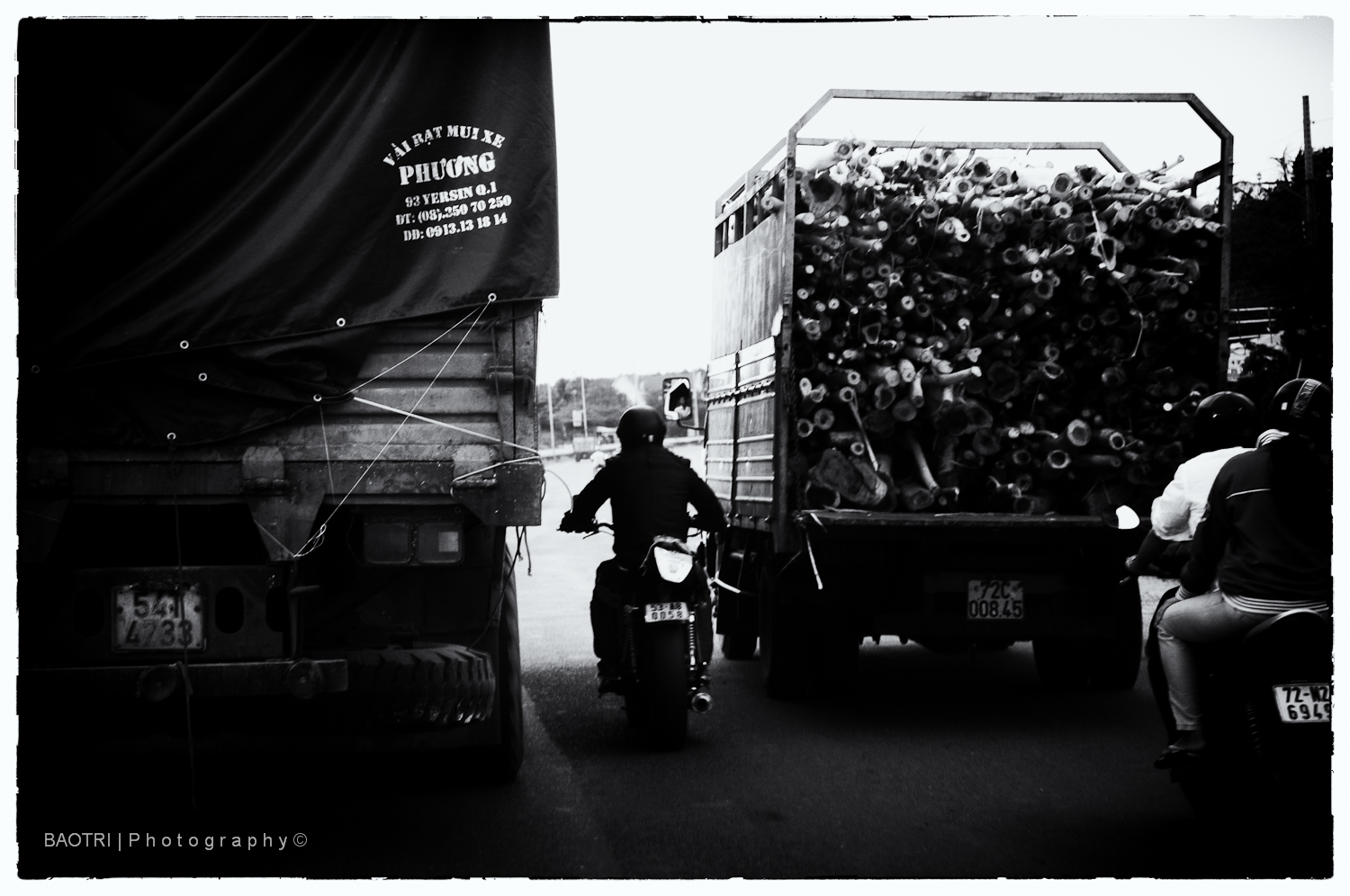 an old black and white po of a person on a motorcycle in front of a big truck full of people