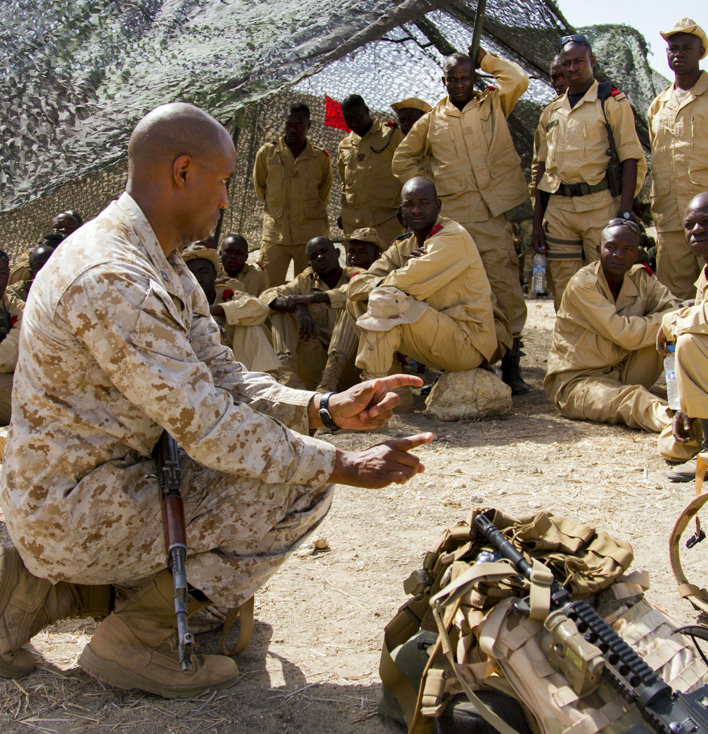 a man in uniform sitting next to soldiers with guns