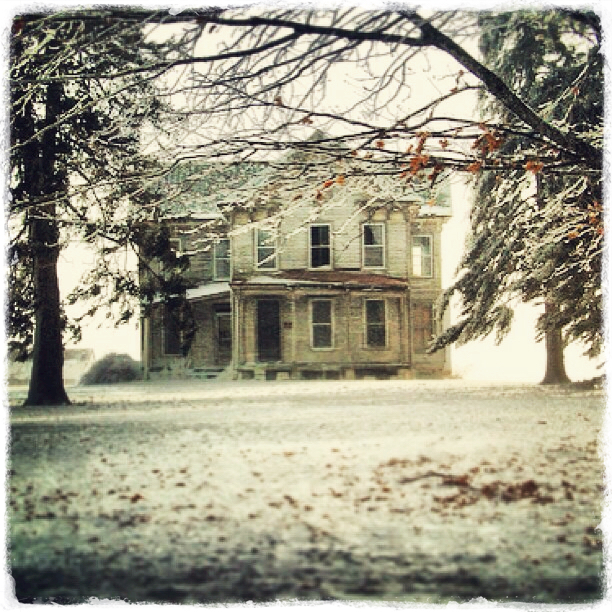 the old house sits next to the trees during a snowy day