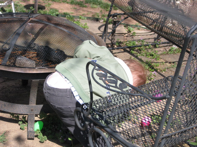 a baby asleep on the ground in front of a fire pit