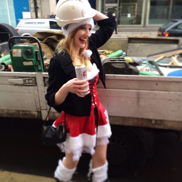 a woman dressed up in santa clause garb, holding a soda