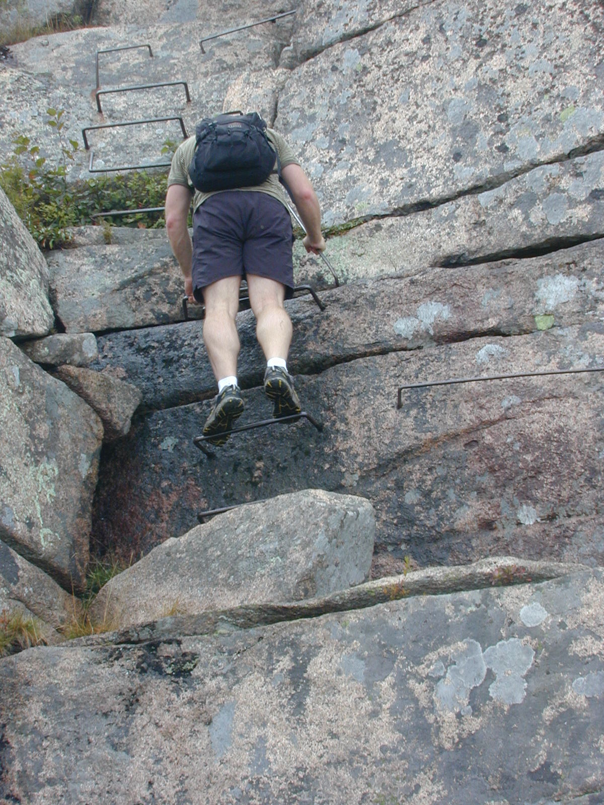 a man is climbing over the rocks wearing shorts and a backpack