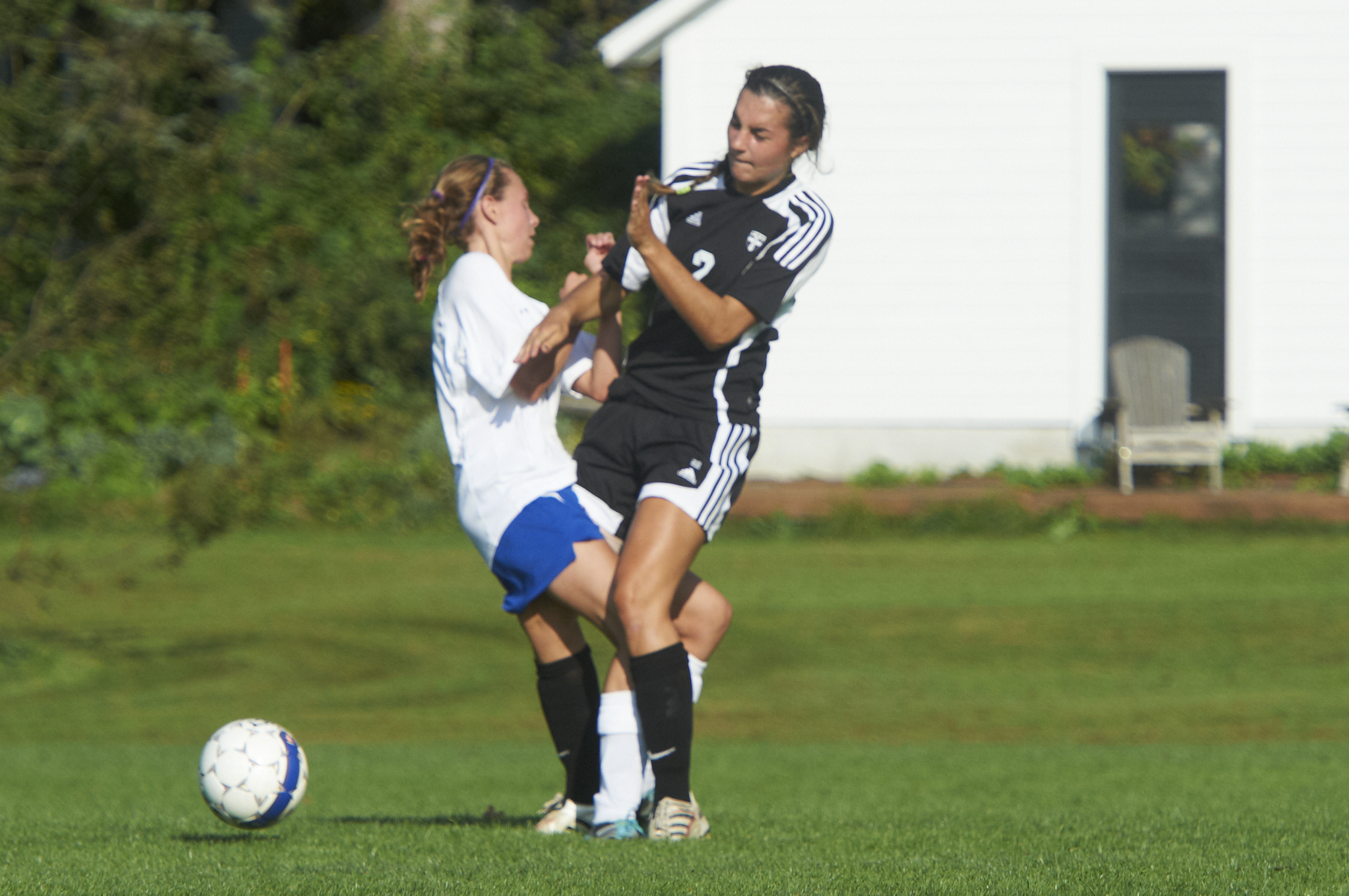 two women playing soccer with a white ball