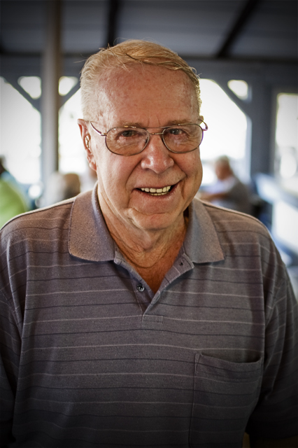 an old man wearing glasses and smiling at the camera