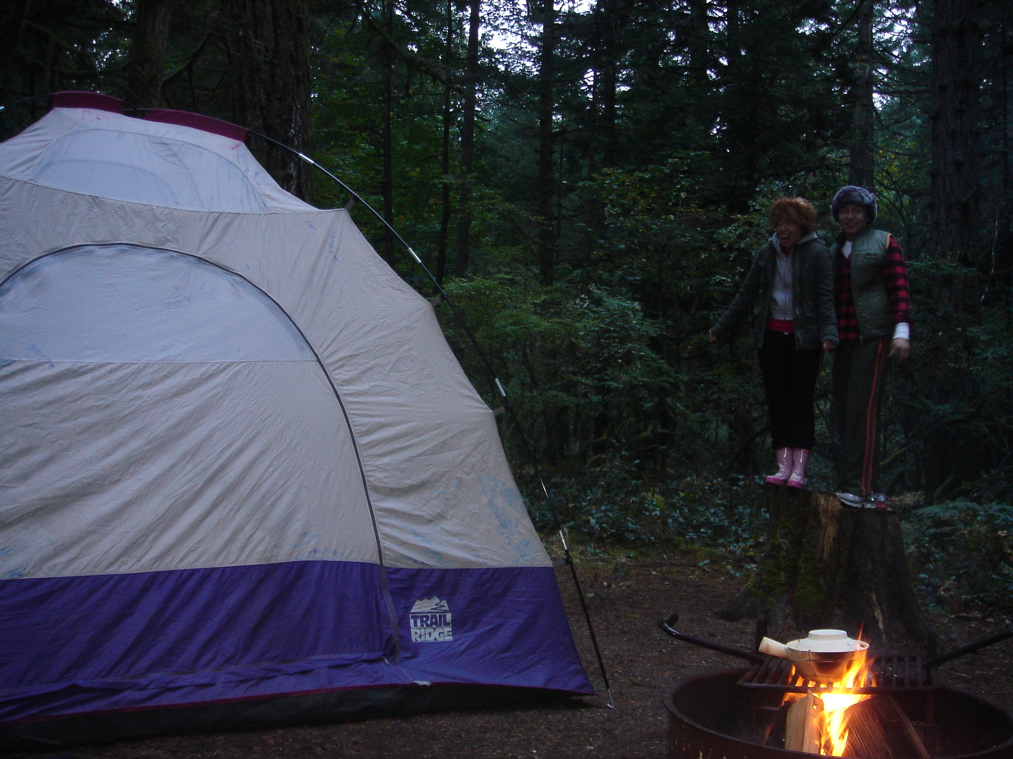 two girls with backpacks standing outside a tent