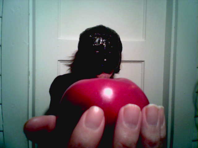 the hand is holding a large red object