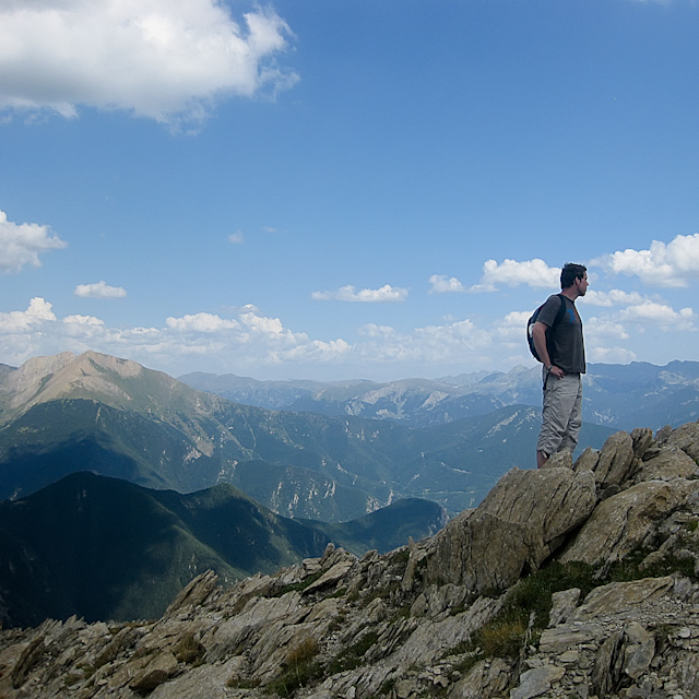 a man on the top of a mountain looking at the view