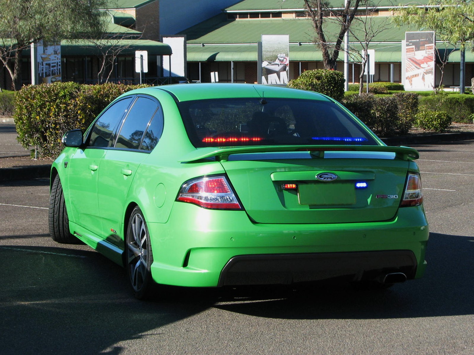 a green car with its back lights on in a parking lot