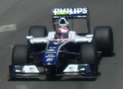a man driving on the back of a blue racing car